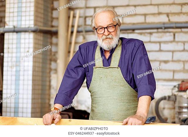 retired man in working outfit making rennovation in the garage. close up portrait