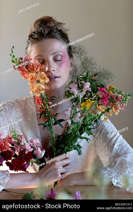 Beautiful woman with blush on face holding wildflowers in studio