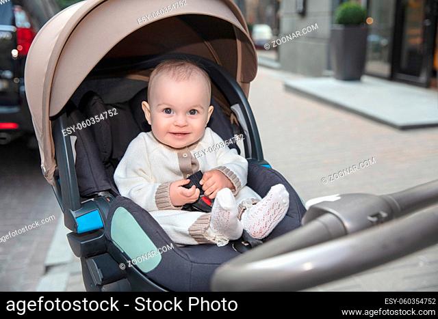 Happy little baby sitting in a stroller outdoors