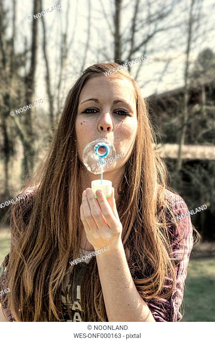 Germany, Portrait of teenage girl blowing bubbles