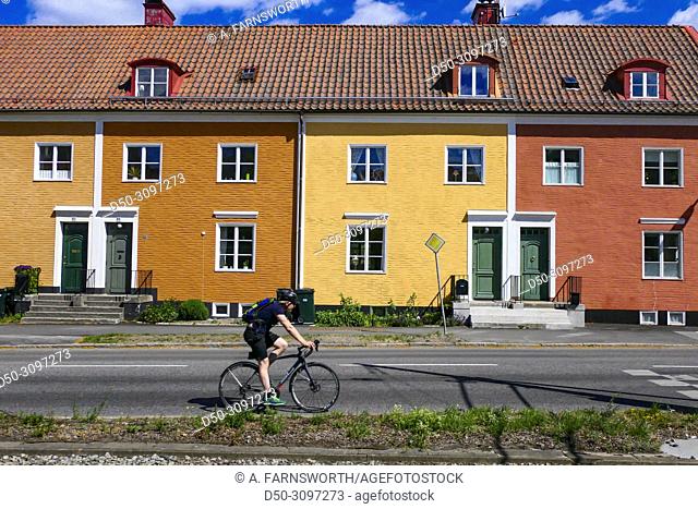 Stockholm, Sweden A bicyclist riding by brightly colored houses along Alviksvagen in Appelviken