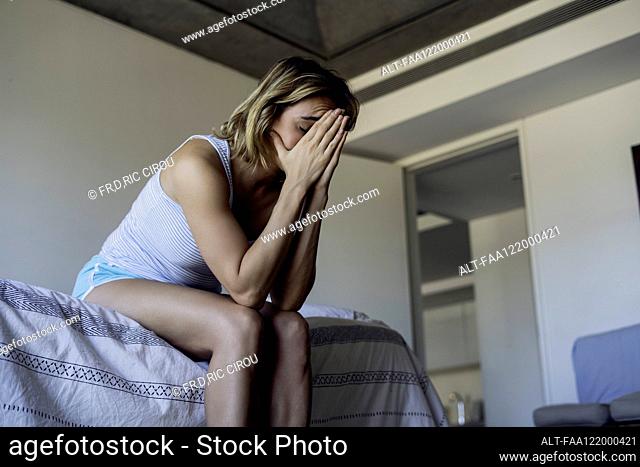 Stressed woman sitting on bed