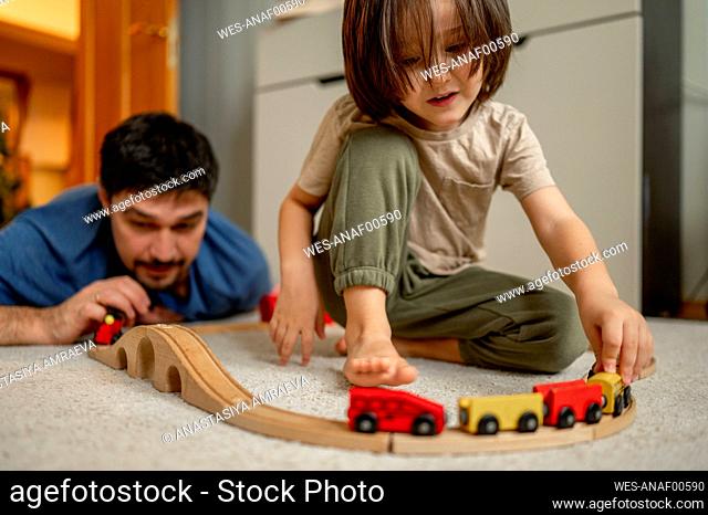Father and son playing with wooden toy train at home