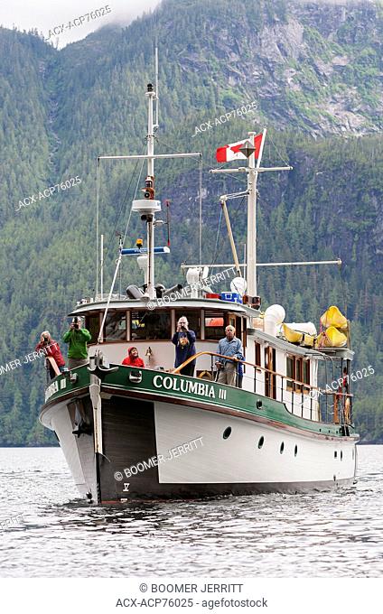 Photographers aboard Columbia III prepare to photograph a waterfall cascading into Kynoch Inlet. Fjordland, Great Bear Rainforest