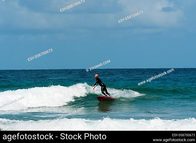 A young athletic man surfing waves in the Atlantic on the coast of Brittany on a summer day