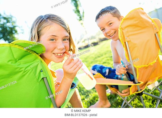 Caucasian children drinking soda in backyard