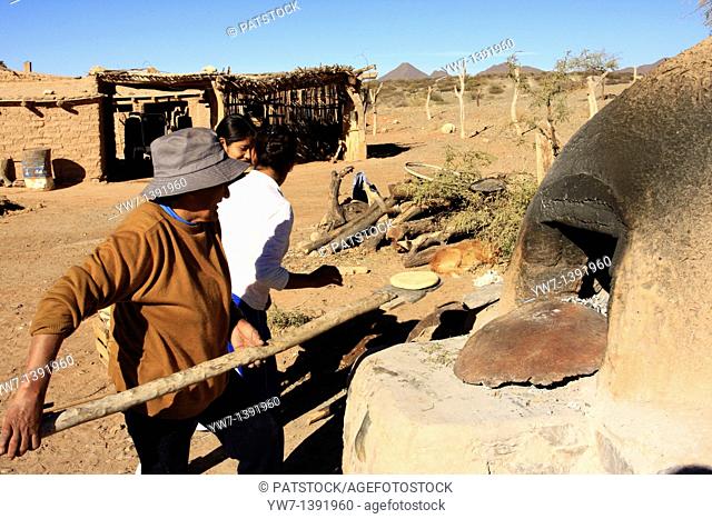 Women are baking bread in an oven made of adobe brick, in Calchaqui valley, Salta province, south of Cachi, Argentina
