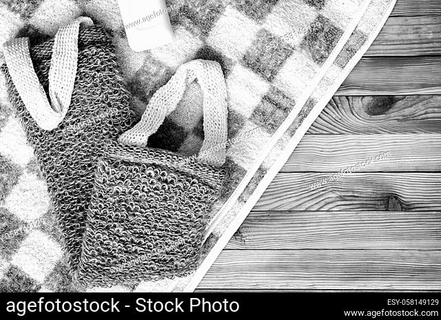 Accessories for visiting the bath or sauna on a wooden background: towel, washcloth. Top view with copy space. Flat lay