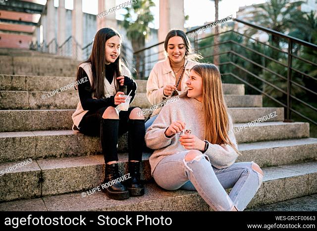 Female friends eating ice cream while sitting on steps
