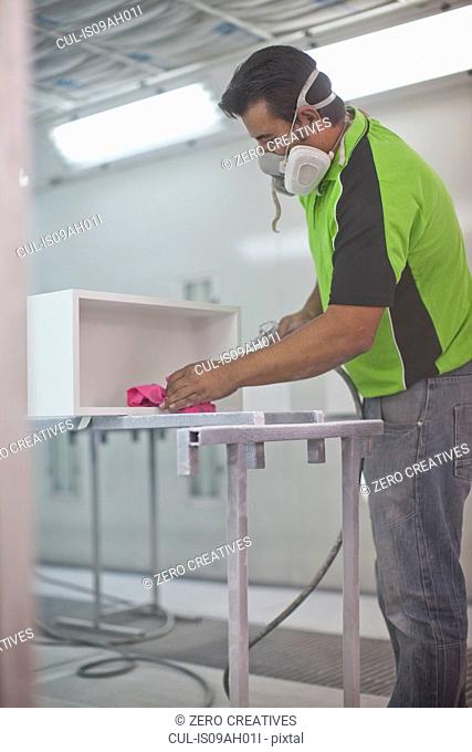 Man spraying wooden box in carpenters workshop