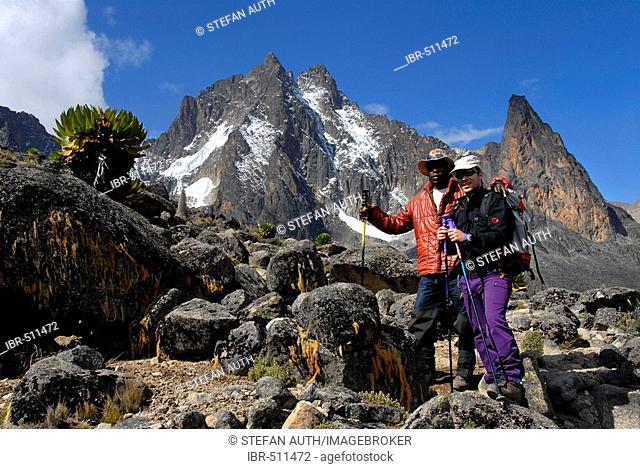 Mountaineerers among rocks below snow covered summit Batian (5199 m) Mount Kenya National Park Kenya