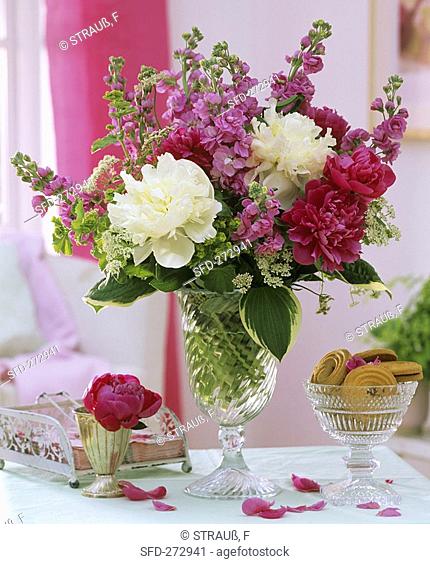 Arrangement of peonies and stocks, bowl of biscuits