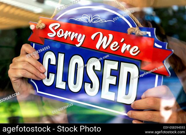 Female Store Owner Turning Sign to Closed in Window