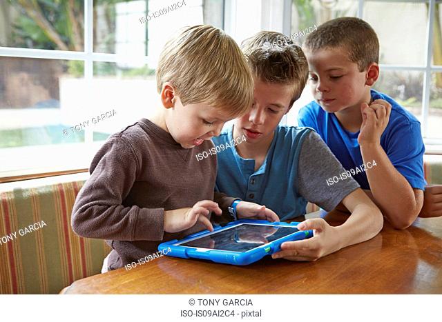 Three boys playing with digital tablet