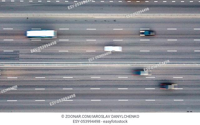 Aerial view shooting from drone on multi-lane highway in the evening, cars with headlights and parking lights included. Speedway, asphalt road