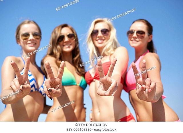 summer vacation, holidays, gesture, travel and people concept - group of smiling young women showing peace or victory sign over blue sky background