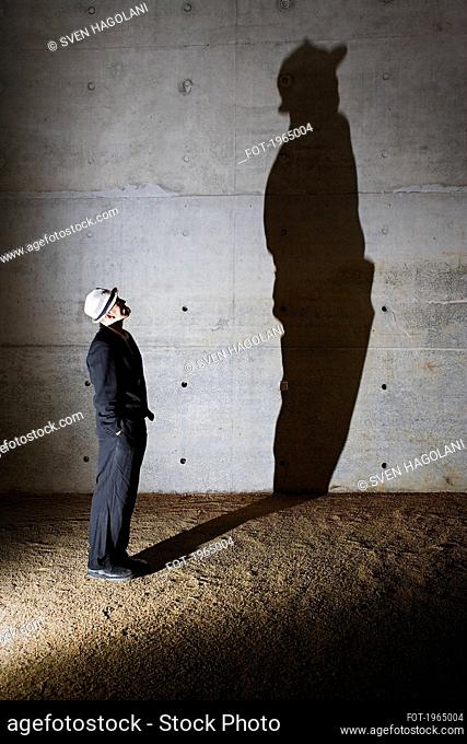 Man looking up at tall shadow on wall