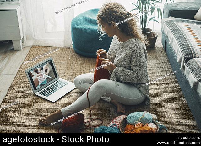 Woman at home doing knit work for hobby and leisure activity alone watching tutorial on line on internet channel. Concept of people and diy work indoor