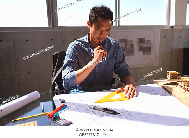 Male architect working on blueprint at desk