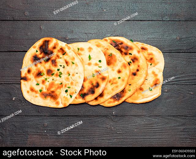 Fresh naan bread on dark wooden background with copy space. Several perfect naan flatbreads top view or flat lay