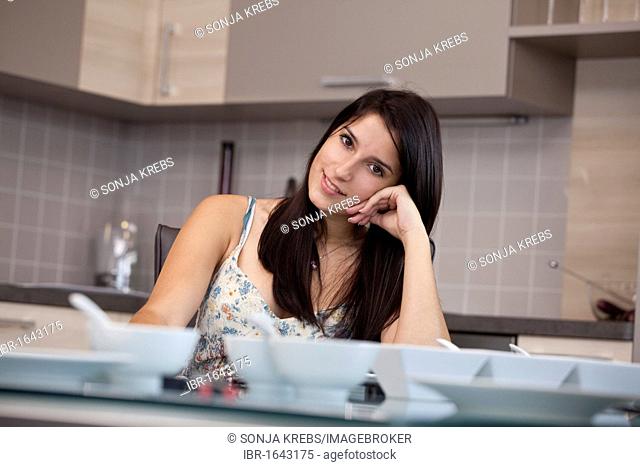 Young woman sitting at the dining table in the kitchen and relaxed
