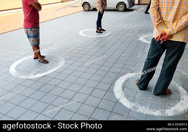 People Practice Social Distancing Outside Grocery Store. Customers Standing Inside Circle At two meters Distance To Prevent The Spread Of COVID-19