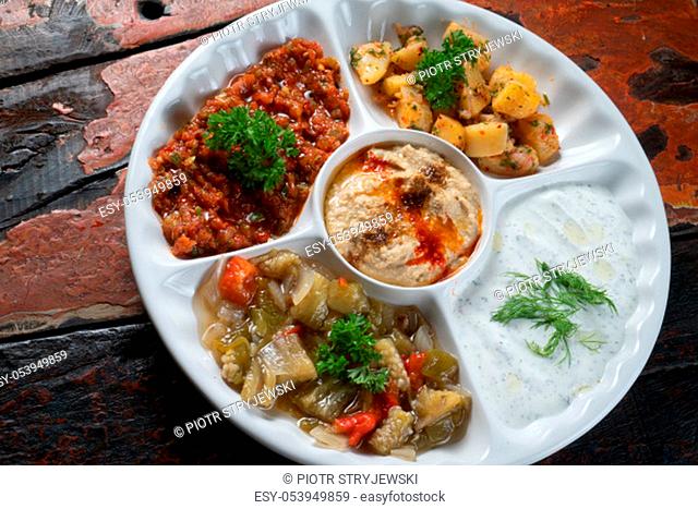 Mix plate Arabic food with vegetarian spread starters isolated on rustic wooden background