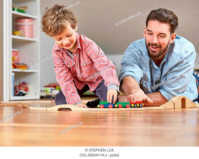 Father and son playing with wooden toy train set
