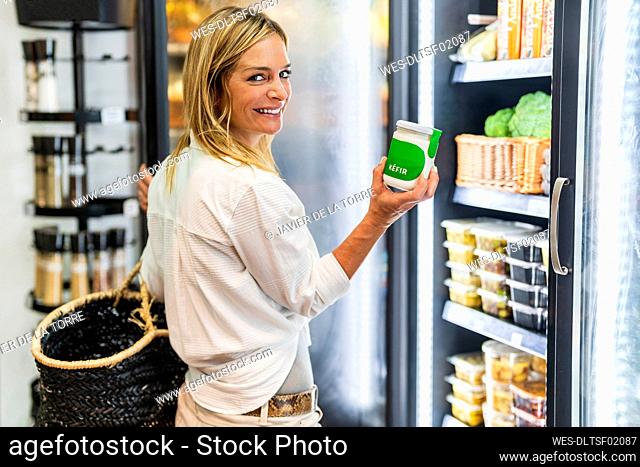 Smiling woman holding jar while shopping at organic store
