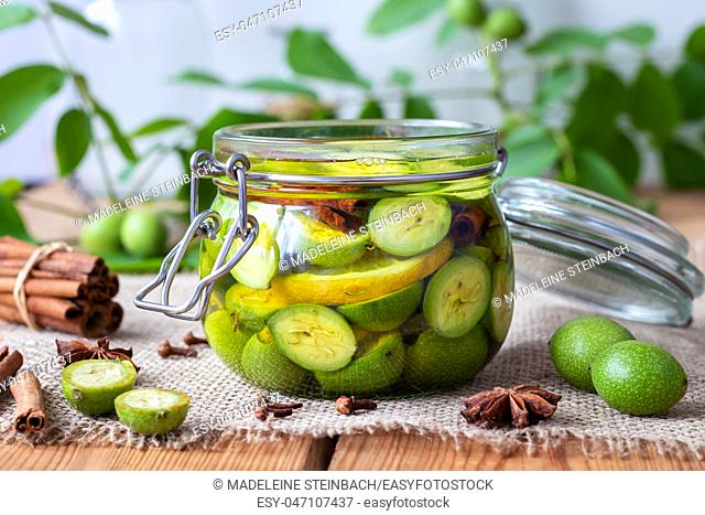 Macerating unripe walnuts, lemon and spices in alcohol in a jar, to prepare homemade tincture