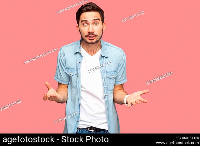 Portrait of angry shocked handsome bearded young man in blue casual style shirt standing and looking at camera and asking