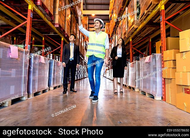 Portrait of engineer manager giving tour two businessman to inspect factory warehouse and discuss about warehouse inventory