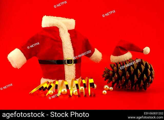 New Year and Christmas scene on festive red background with with santa costume and cedar cone with red Santa hat