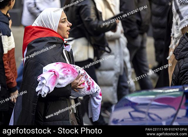 11 November 2023, North Rhine-Westphalia, Wuppertal: A woman carries a bundle of cloth symbolizing a deceased child in Gaza during a demonstration under the...