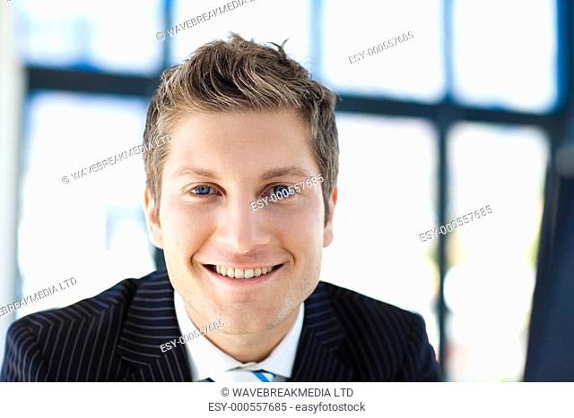 Attractive young businessman smiling at the camera in office