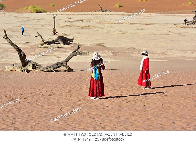 Asian tourists in long, sun-protective clothes take pictures in Dead Vlei, taken on 01.03.2019. The Dead Vlei is a dry, surrounded by tall dune clay pan with...