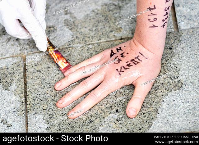 17 August 2021, Berlin: A policeman tries to remove an activist's stuck hand from the ground during a blockade of the entrance to the German Farmers' Union