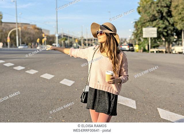 Young woman commuting in the city, hailing a taxi