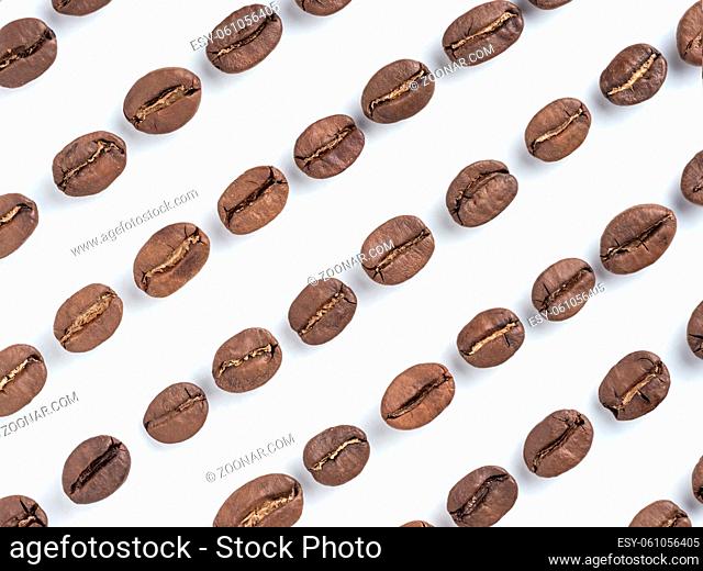 Diagonal rows of coffee beans closeup on white background. Top view or flat lay