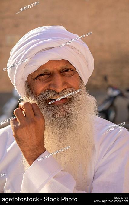 AN OLD MAN WITH TURBAN HAPPILY POSING FOR CAMERA