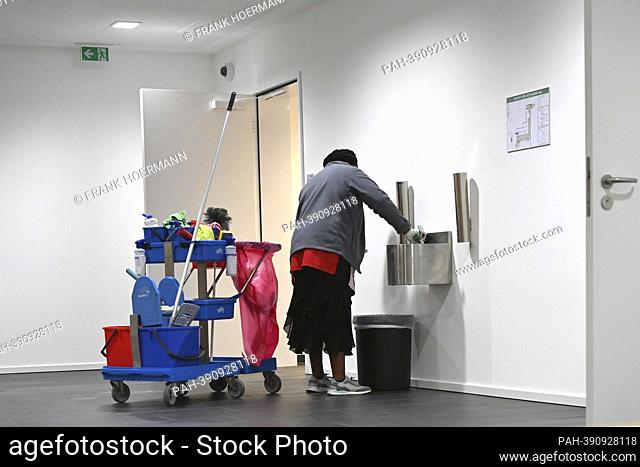Cleaner at work with cleaning trolley, dark-skinned, colored cleaning lady, cleaning, minimum wage, , working hours, wages, dumping wages, marginally employed