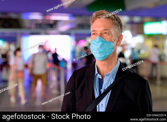 Portrait of mature businessman with mask for protection from corona virus outbreak at the sky train station