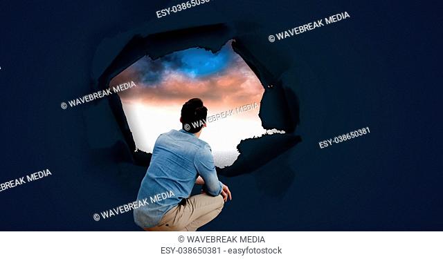 Man looking through surreal paper hole at sky