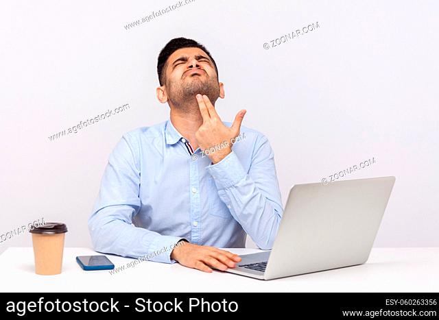 Upset depressed male employee sitting office workplace with laptop on desk, pointing finger gun gesture to head, committing suicide from stressful job