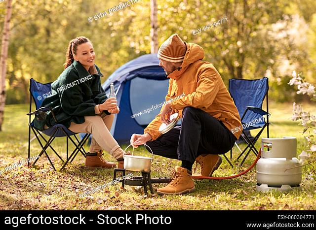 couple drinking beer and cooking food at tent camp