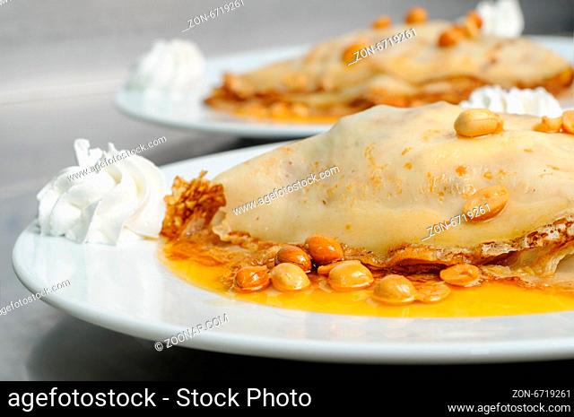 pancake crepe with peanuts and honey decorated with whipped cream