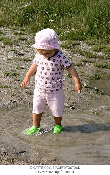 Young girl having fun in a puddle on a warm summer morning  MR