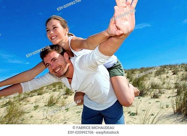 Man giving piggyback ride to girlfriend on a sand dune