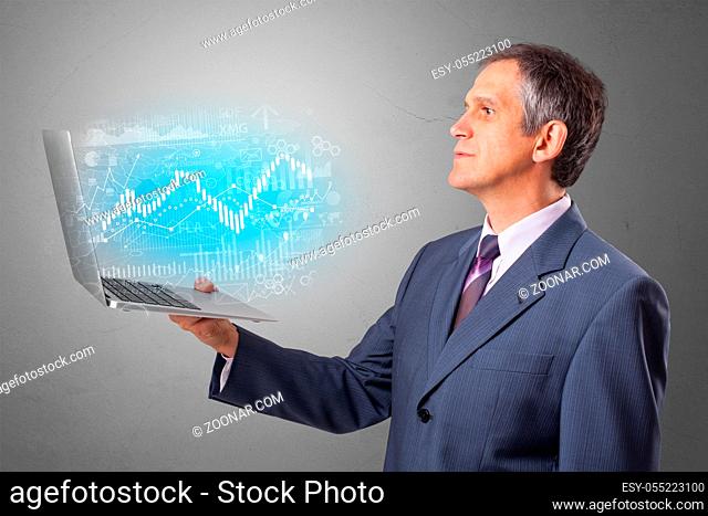 Man holding laptop projecting financial information, diagrams and charts