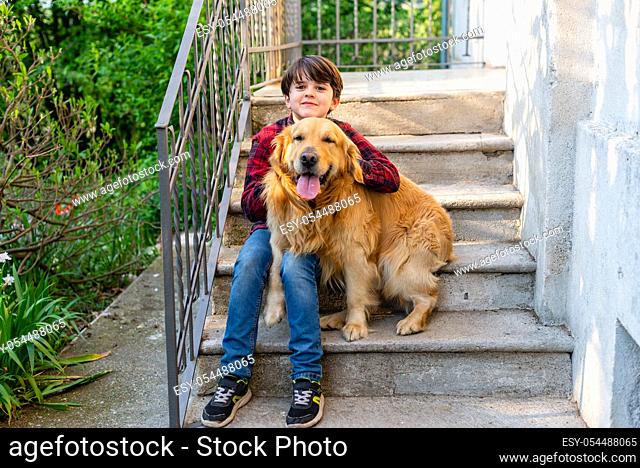 child sit on the stairs with dog - portrait of kid eleven years old and golden retriever togheter on the stairs out home